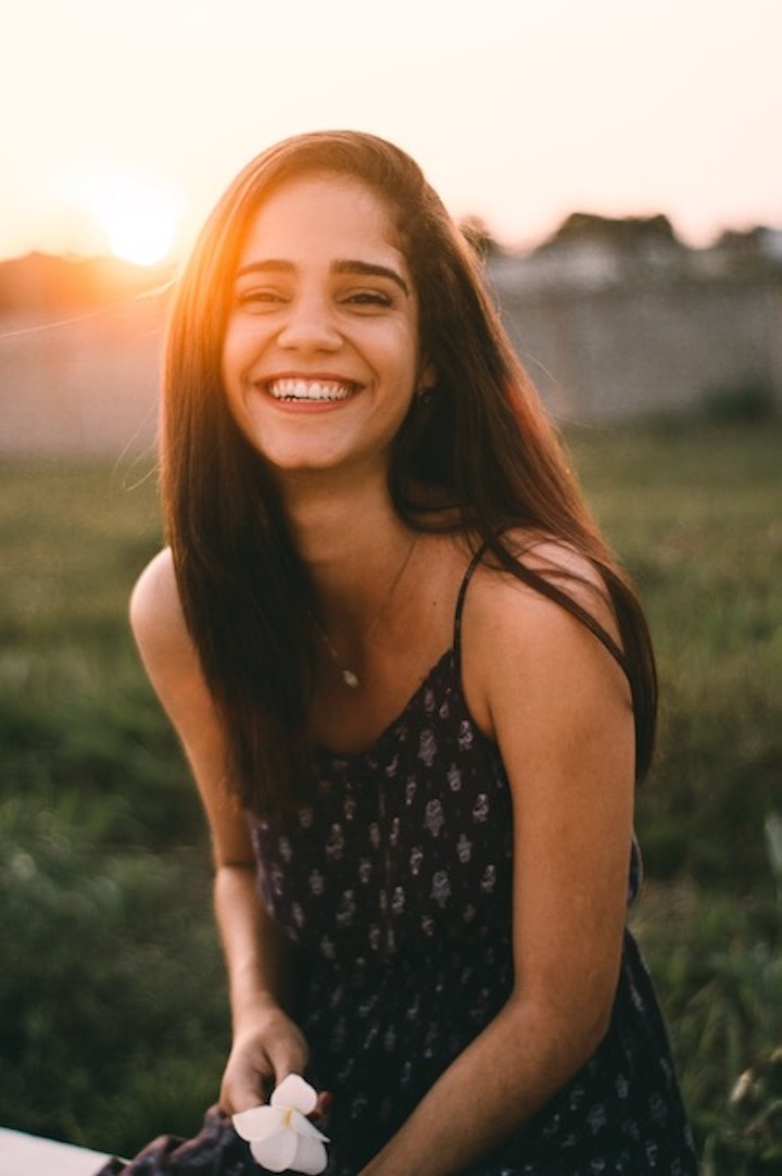 Girl smiling in field at sunset